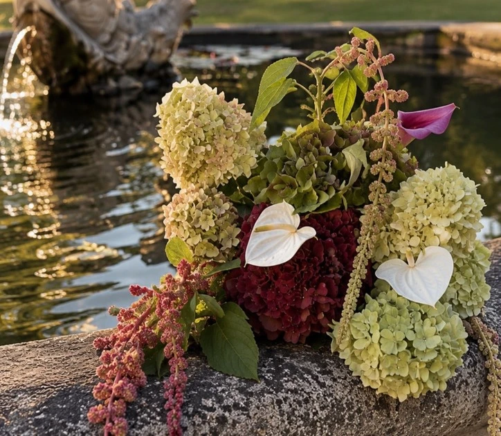Composition généreuse d’hortensias, d’anthuriums et de fleurs bordeaux au bord de l’eau
