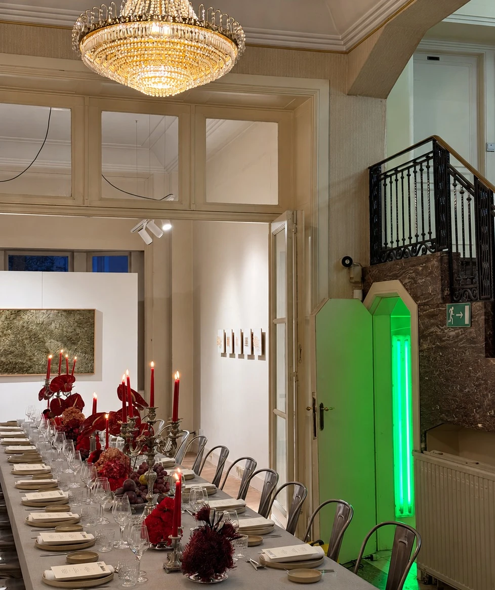 Longue table de dîner ponctuée de fleurs rouges, dans un salon ancien