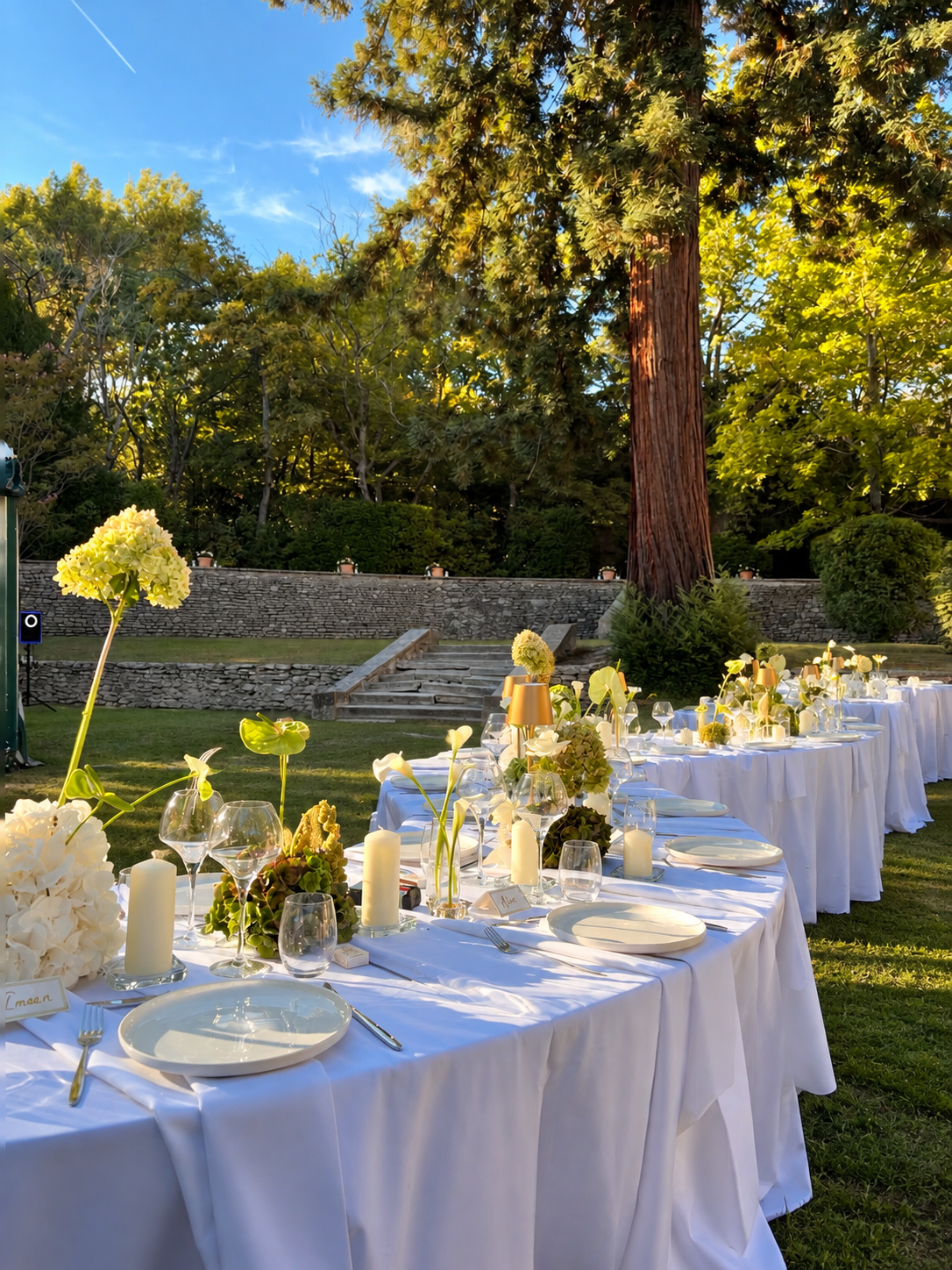 Longue table blanche et compositions vertes et blanches dans le jardin