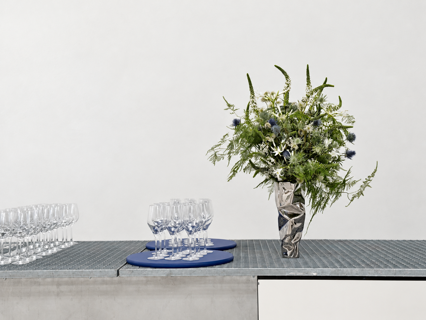 Composition de feuillages et de fleurs blanches sur un bar gris